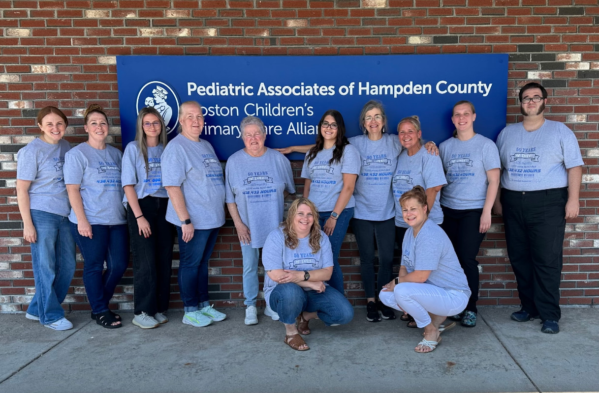 a group of twelve medical providers in front of a building and sign