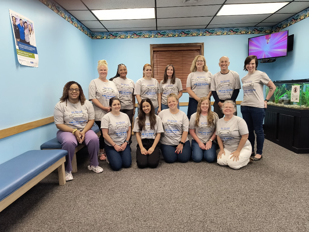 a group of thirteen medical providers in the lobby of a pediatric office